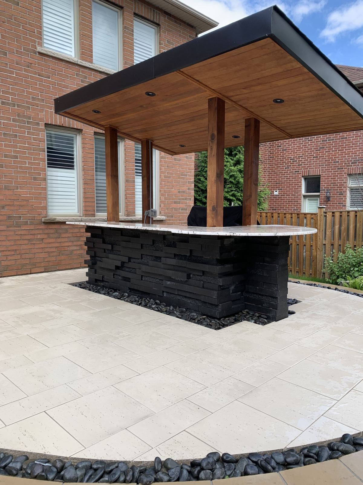 Outdoor kitchen with cantilevered roof and travertine patio