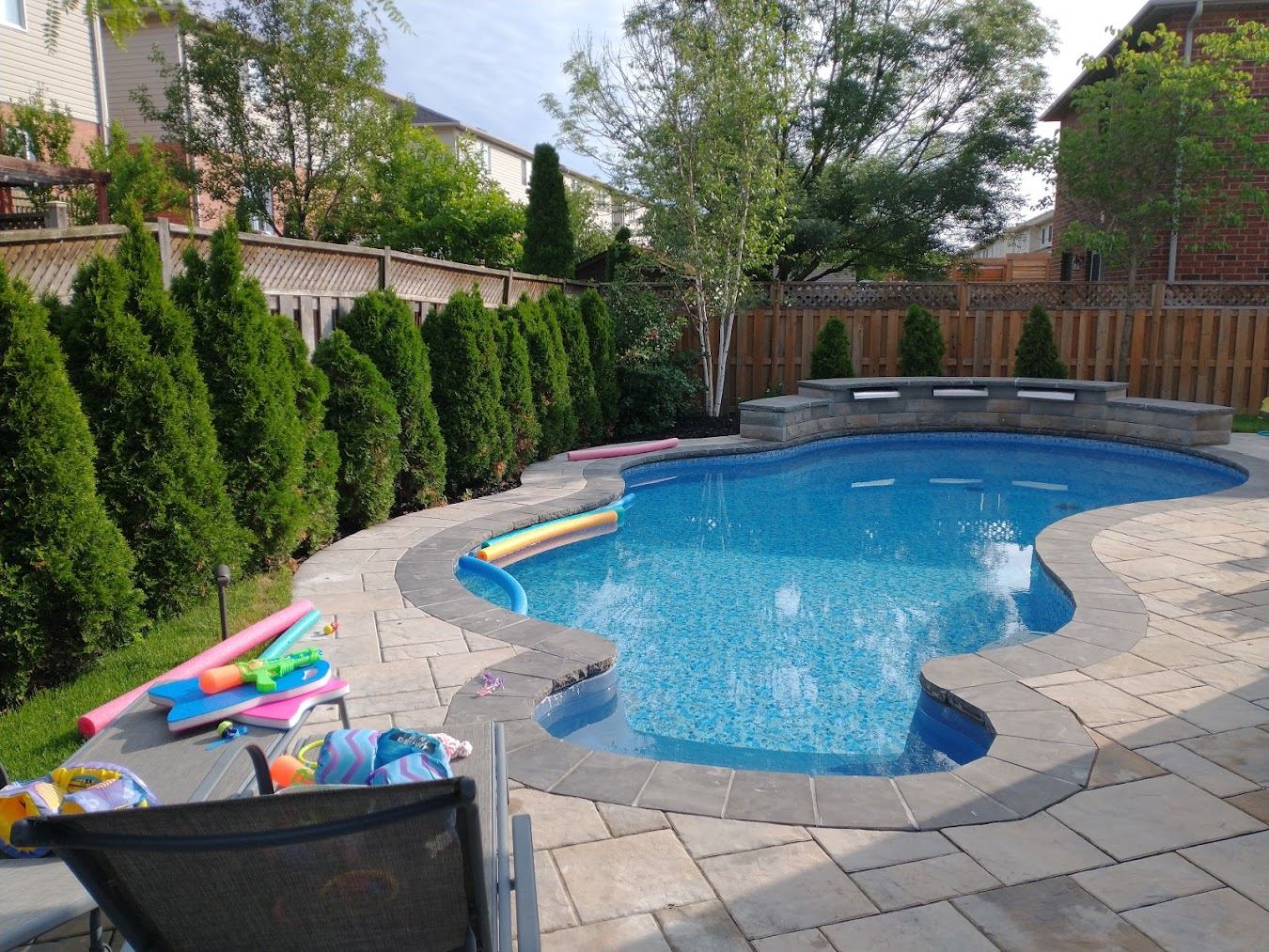 Inground pool with arborvitae privacy screen and paver deck