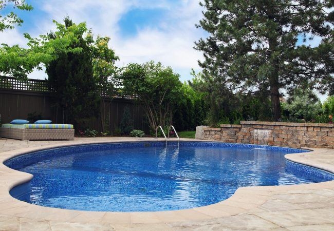 Inground pool with stacked stone waterfall wall and stone coping